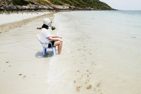 女孩戴上防毒面具坐在椅子上在海