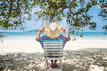 坐在一棵树下享受夏天大沙滩椅上的女人