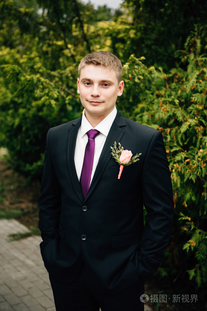时尚新郎在婚礼那天在公园里的肖像