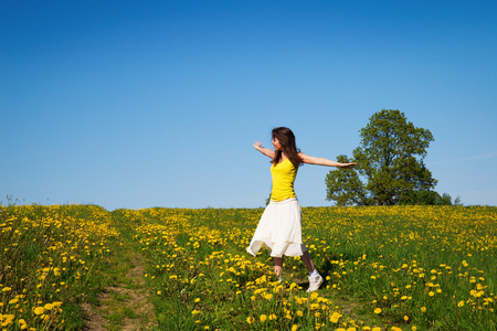 年轻的女子在一片草地蒲公英春天的时间