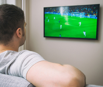 男人在家里的电视上看足球比赛照片