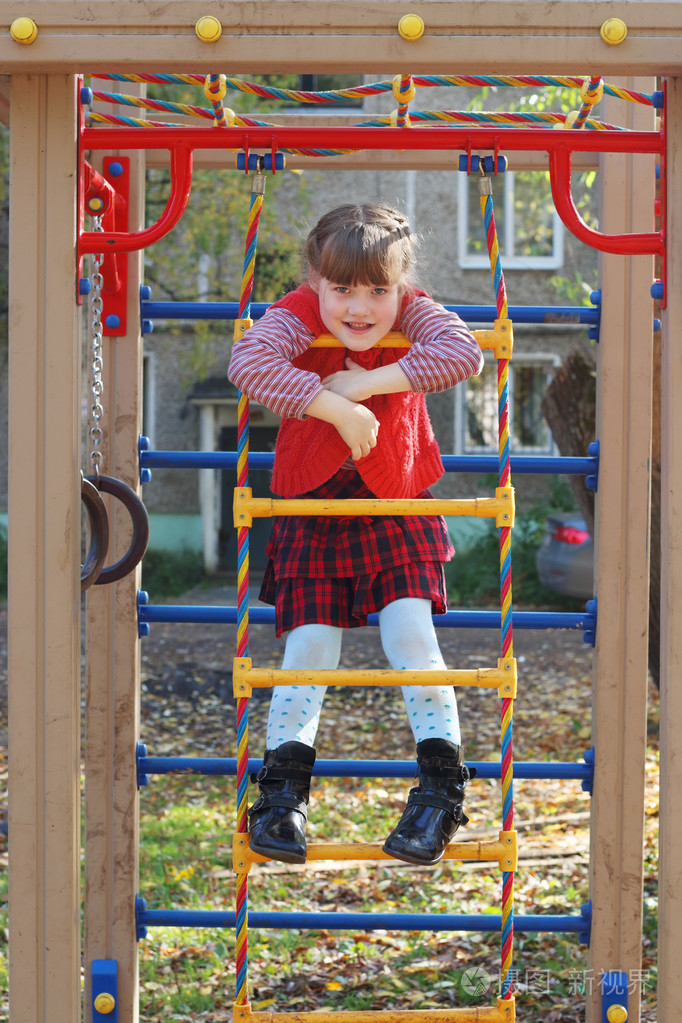 小女孩高兴地微笑在阳光明媚的 autu 梯子操场上