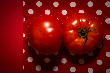 两个红色的西红柿，躺在红色背景与红色茶巾