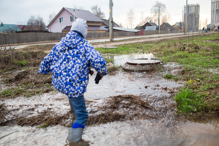 小男孩和一组五颜六色的雨靴.站在伞下的金发孩子.