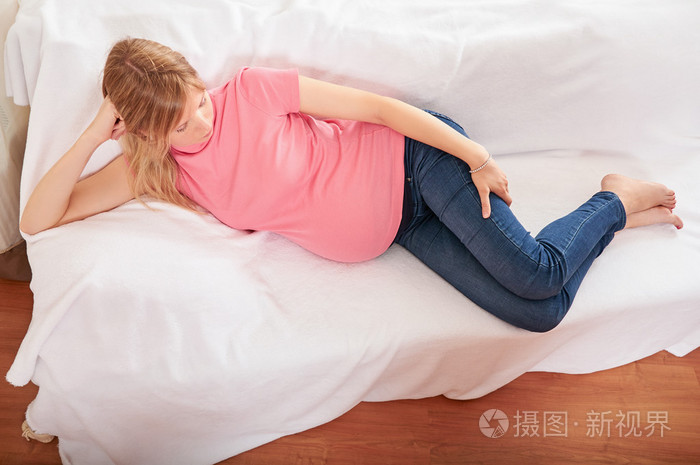 怀孕的女人在家里坐在沙发上放松