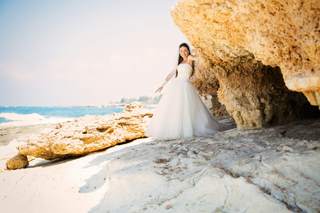年轻漂亮的女人新娘穿着婚纱时在海滩上的室外肖像