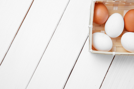 木制白色背景篮子中的新鲜鸡卵