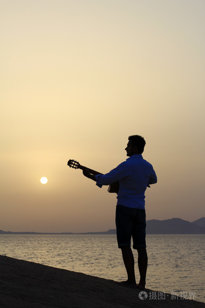 男子在海滩上玩吉他