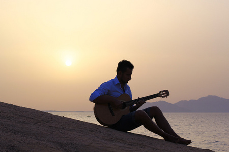 男子在海滩上玩吉他