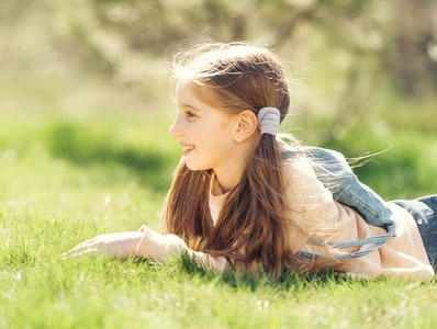 可爱微笑的小女孩躺在草地上