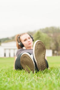 躺在草地上盘腿的年轻女人听音乐