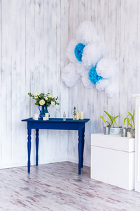 室内设计，白色的花，蓝色与白色的木制背景表上有一个蓝色花瓶中的玫瑰