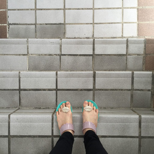 女人的腿和脚在翻转的拖鞋站在户外楼梯第一人称视图照片