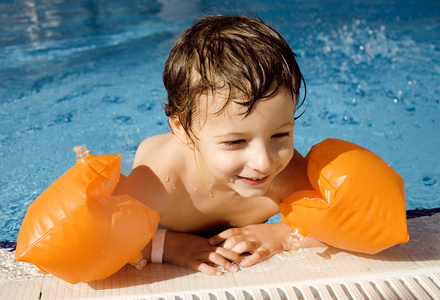 小可爱的真正的男孩在游泳池关闭了微笑