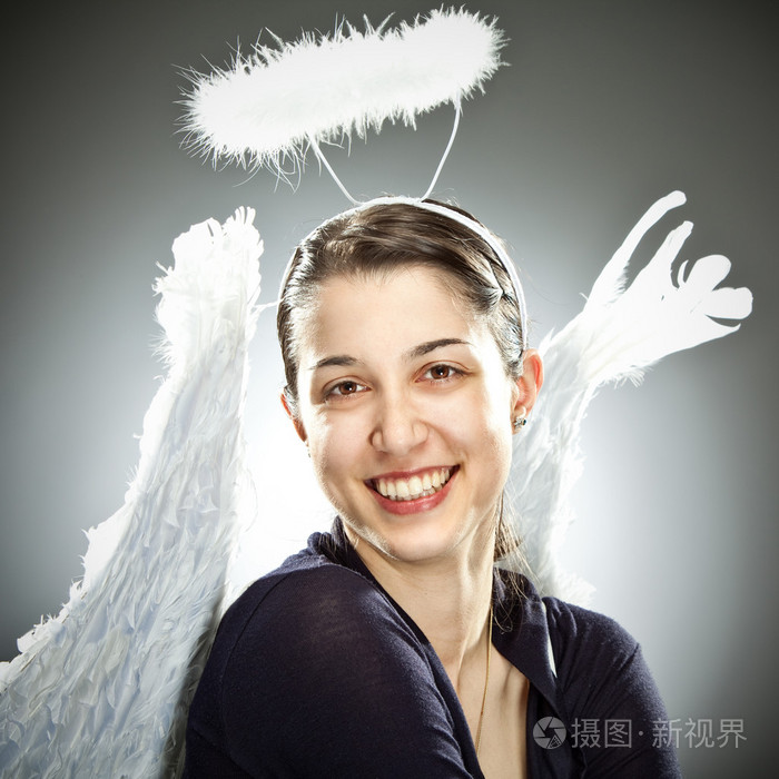 在灰色的背景上可爱的美丽天使年轻女子微笑