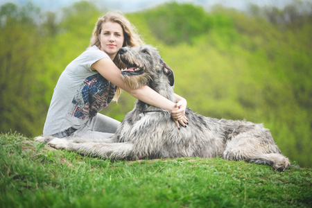 长光头发的女孩抱着一只巨大的灰狗