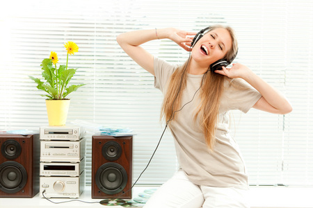 年轻漂亮的女人听着耳机在客厅里的音乐