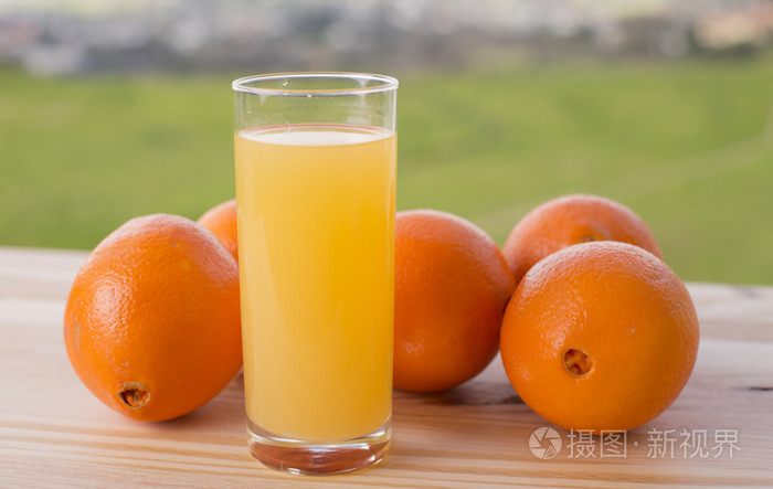杯美味橙汁和在花园里的桌子上的橘子