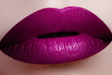 用光滑的紫红色口红特写女人嘴唇。 香水