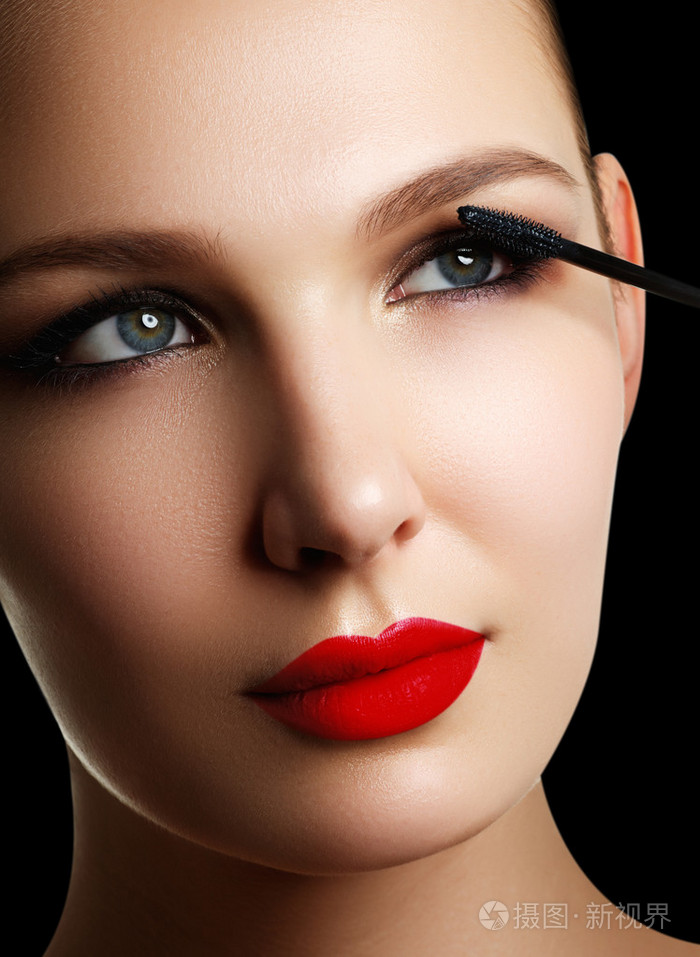 年轻漂亮的女人化妆睫毛膏在眼睛上的画笔