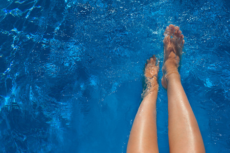 在蓝色的海水游泳池的女人腿