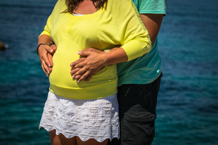 孕妇和她的丈夫牵着她的手在她的婴儿屁股