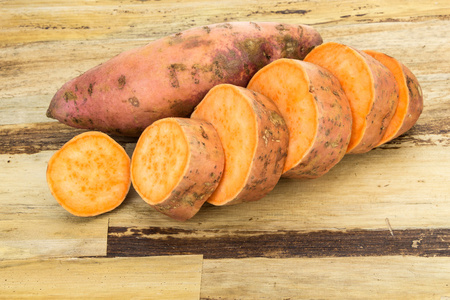 鲜甜土豆整个和切成薄片，木质的背景