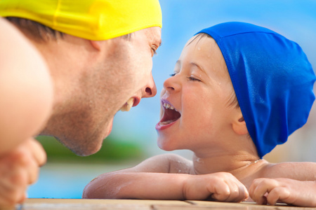 快乐的孩子和爸爸游泳池盖在池中有乐趣