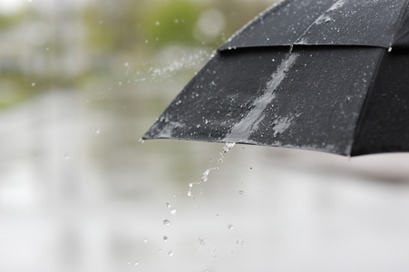 带着闭伞的穿着橡胶靴的女人小女孩和男孩带着雨伞在雨中玩耍
