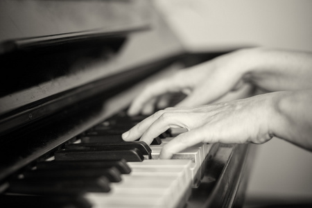 弹钢琴的浅的焦点的两只手的特写。黑色和白色