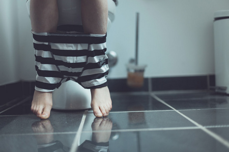 内衣上的男孩在家里用一个厕所的双腿照片