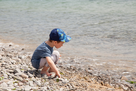 小男孩在沙滩上玩的岩石