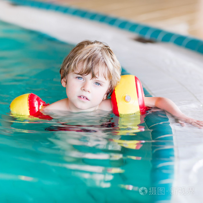 swimmies 学习在室内游泳池游泳的小小孩男孩