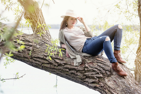 年轻女子坐在一棵树在水边