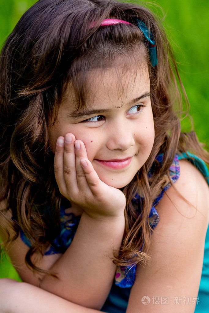 漂亮的小女孩在自然界中阳光明媚的卷发微笑