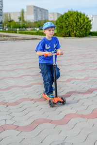 英俊的小男孩站在一个玩具滑板车