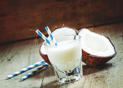 椰子牛奶在玻璃杯里用条纹的吸管和椰子两半