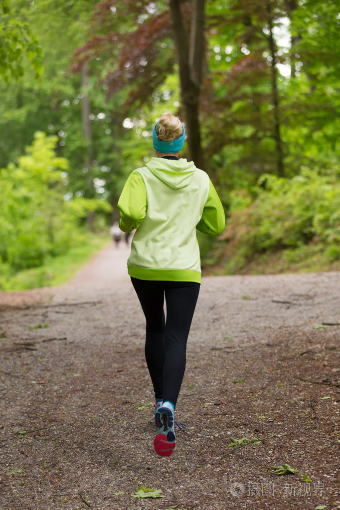 运动年轻的女性跑步者在森林里