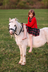 小女孩坐在骑一匹白马，俯视