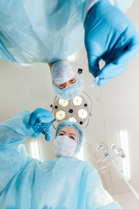 两位外科医生穿着防护服准备操作，看着照相机上的手术灯背景