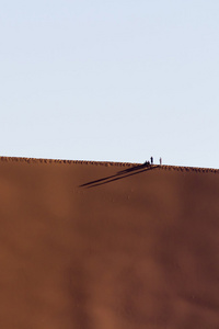 人们在一个红色的沙丘在纳米布沙漠，在纳米比亚的索苏斯