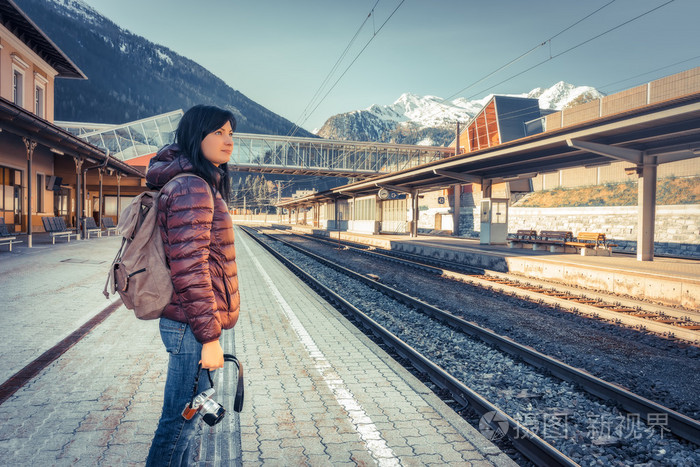 用照相机牵手站在站台等候火车上的女孩