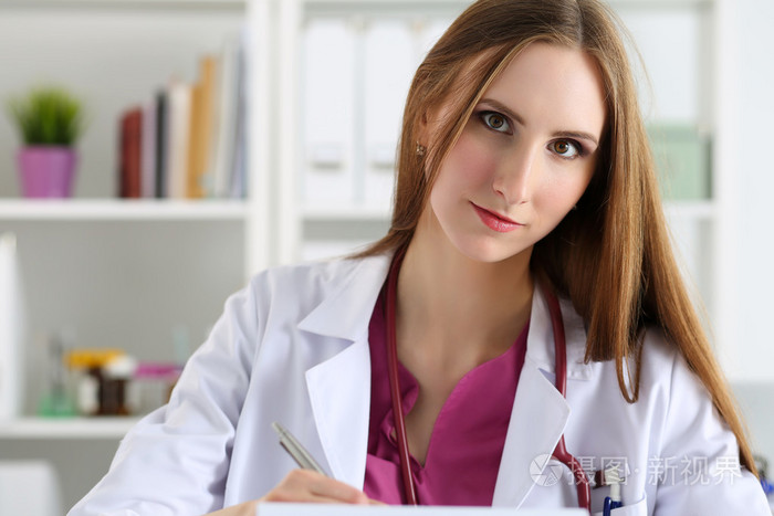 美丽的微笑女医生拿着夹子写字