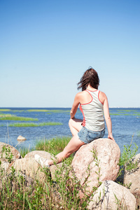 年轻梦想的女人坐在面朝大海的岩石