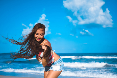 一个漂亮的年轻黑发女孩与长长的头发，蓝色的大海为背景的肖像