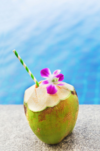 新鲜的椰子饮料兰花与游泳池