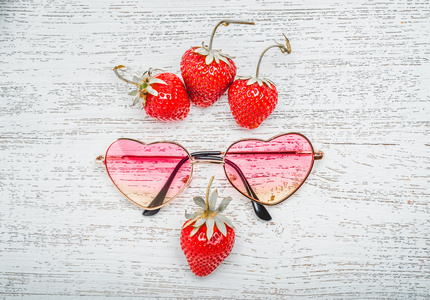 成熟的草莓与太阳镜上木制的背景