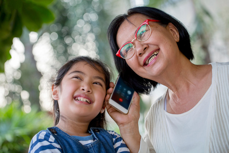 小的亚洲女孩与她的祖母打电话手机