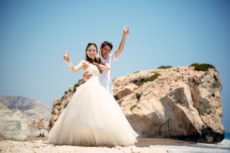 新娘和新郎戴着眼镜的地中海海滩上的香槟