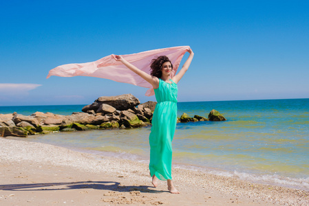 一件漂亮的衣服，用飞的围巾在夏天的海滩上的小女孩
